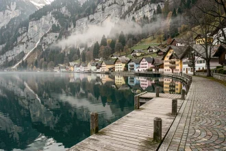 Village de Hallstatt en Autriche hors saison, reflets des maisons colorées sur le lac Hallstätter See par une matinée brumeuse d'automne
