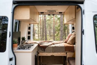 Intérieur aménagé d'un van avec lit escamotable en bois, cuisine compacte et rangements optimisés